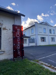 Firmenschild Lamberts Glas mit Gebäude im Hintergrund